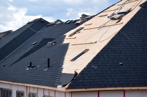 Roofer installing black shingles on a new residential home in Florida