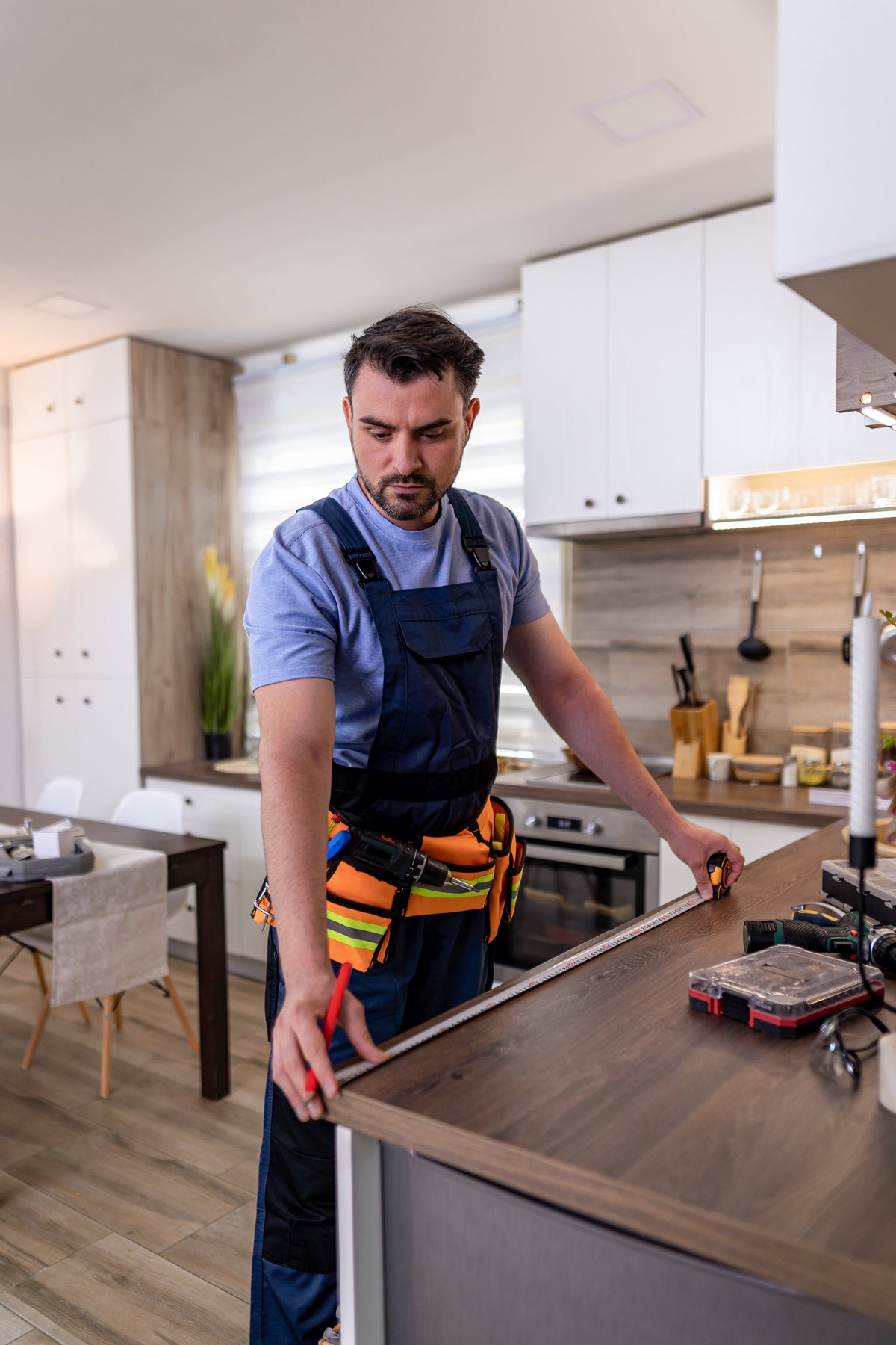 Professional measuring and fitting custom cabinetry in a contemporary kitchen during a remodel