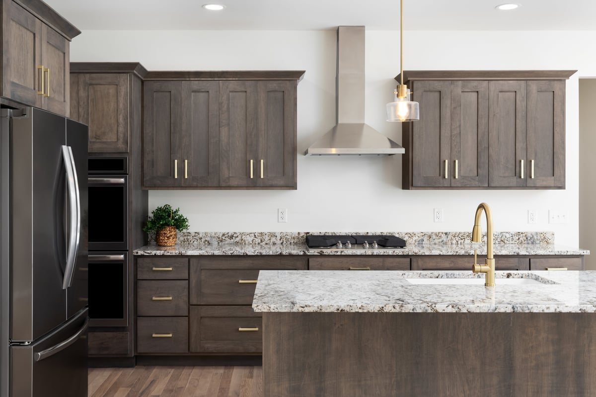 Modern luxury kitchen with dark wood cabinets, granite countertops, and gold fixtures