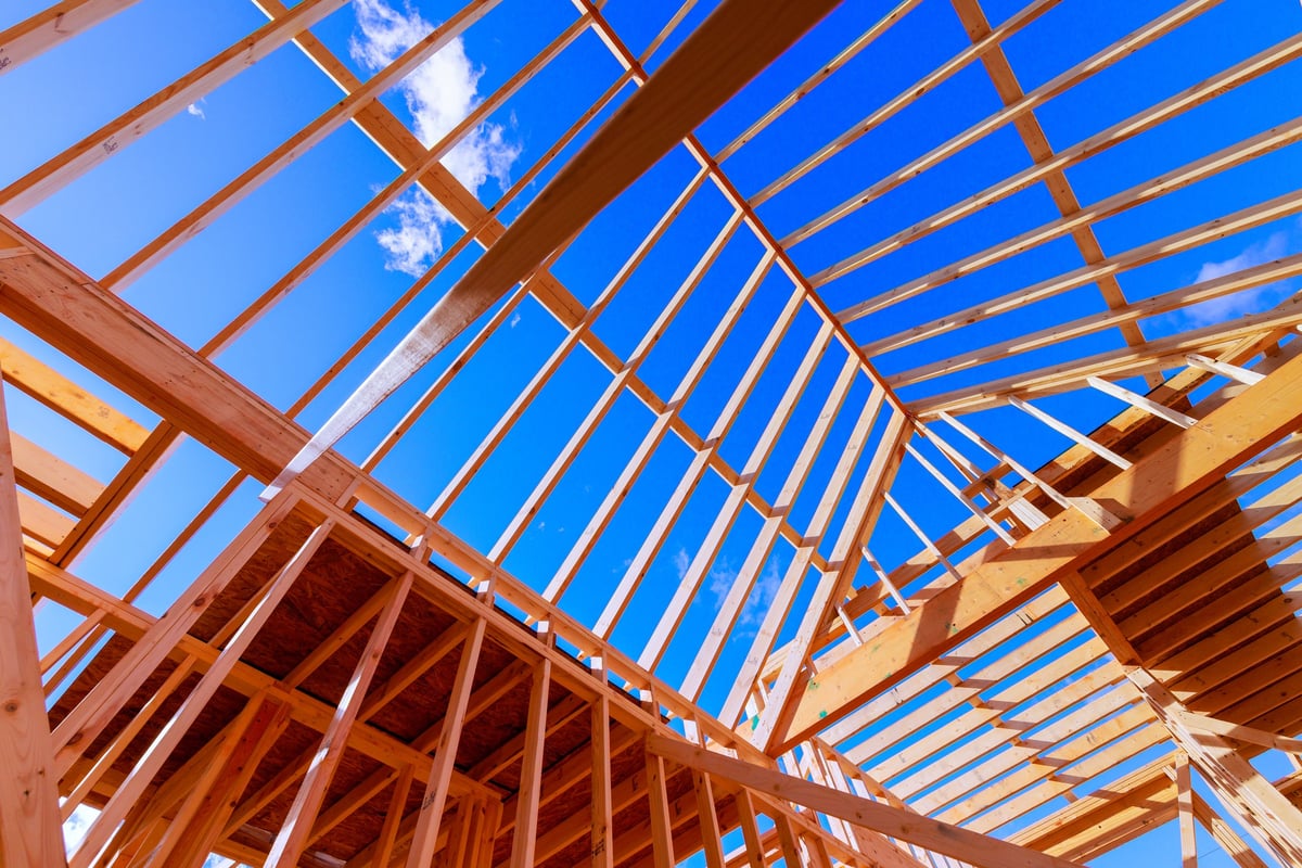 Construction workers framing a residential home addition under roof trusses