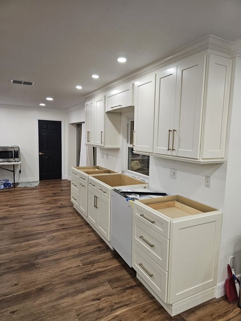 White kitchen cabinets with tall upper storage, drawer bases and appliance opening during remodeling.