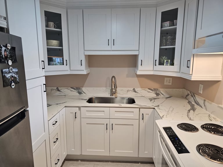 Kitchen renovation in progress with dark shaker cabinets, stainless steel refrigerator and range.