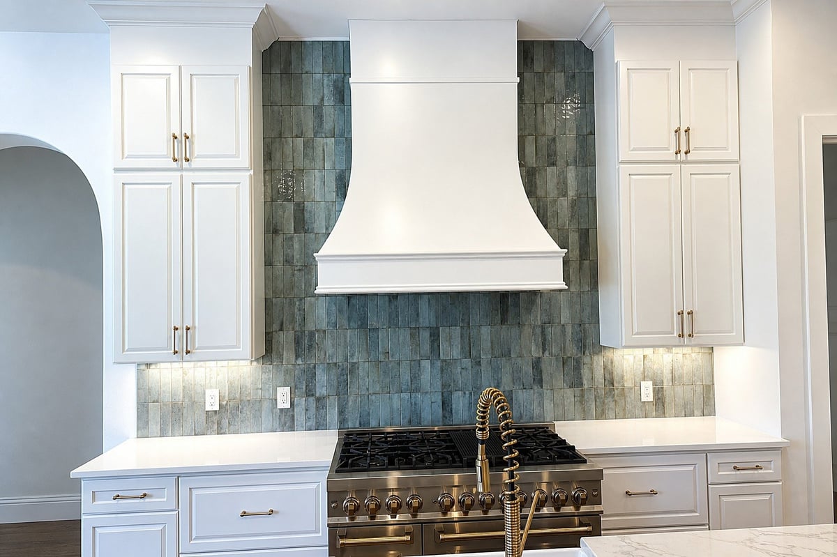 Bradenton kitchen remodel with a curved white range hood, sea-green tile backsplash and white cabinetry.