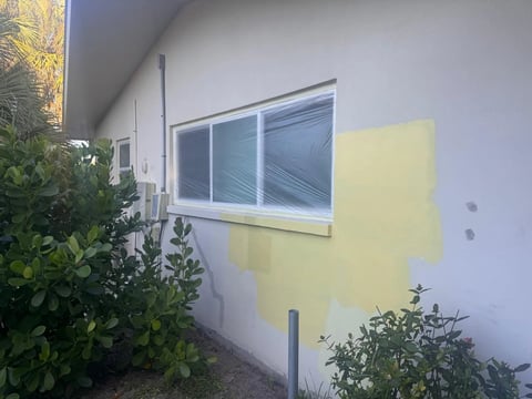 Before / preparation: Window-side exterior wall with a yellow color sample and gray preparation areas.