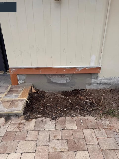 Before / preparation: Vertical entry paneling above exposed wood trim and gray patches at the wall base.