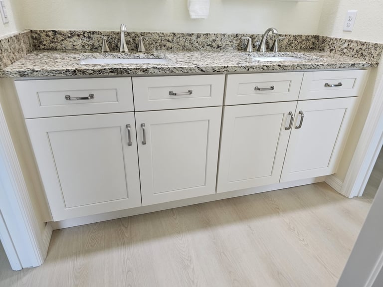 Double bathroom vanity with white shaker cabinetry, two undermount sinks and light speckled countertop.
