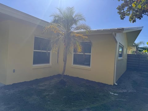 After: Finished yellow exterior corner with two front-facing windows, a side window and a palm tree.