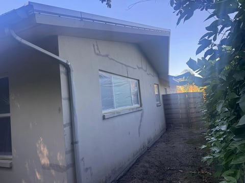 Before / preparation: Side wall and window beneath the gable with visible gray patch lines before the completed finish.