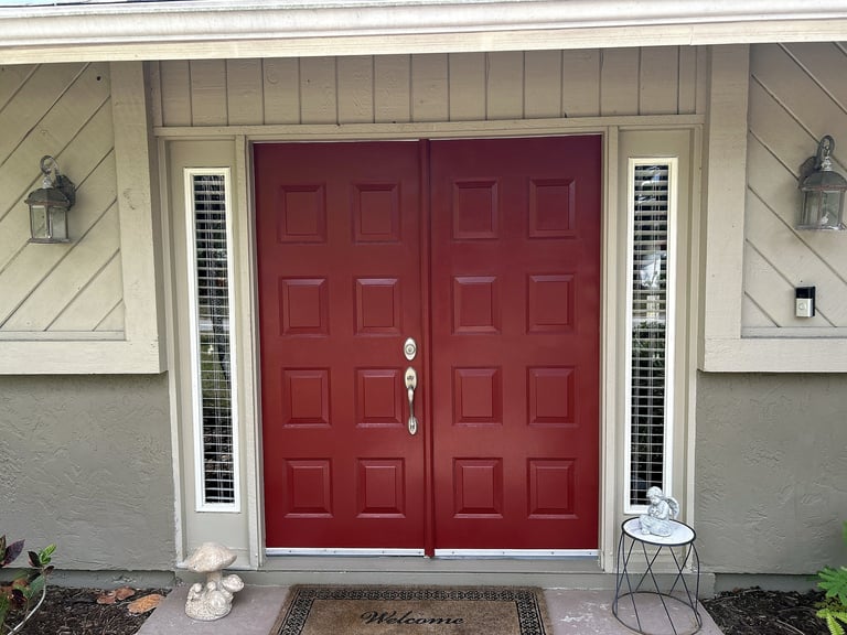 Original red double entry doors with narrow sidelights before replacement.