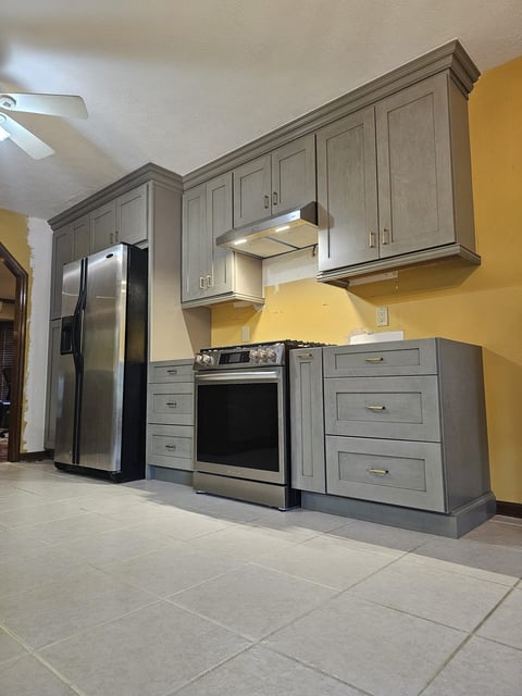 Gray shaker cabinetry with stainless steel range and refrigerator in a kitchen remodel.
