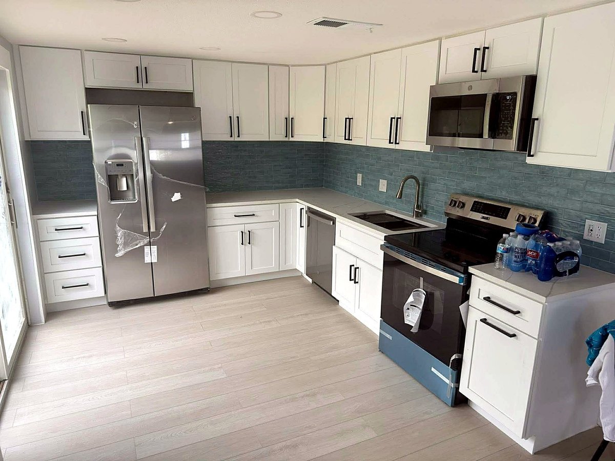 Sarasota kitchen remodel with white shaker cabinets, dark hardware, blue-green backsplash and stainless-steel appliances.