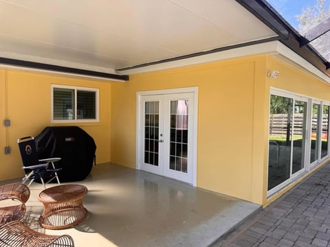 After: Yellow exterior walls around a covered patio with white-framed doors and windows.