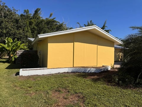 After: Completed yellow gable-end wall above the low retaining wall and lawn.