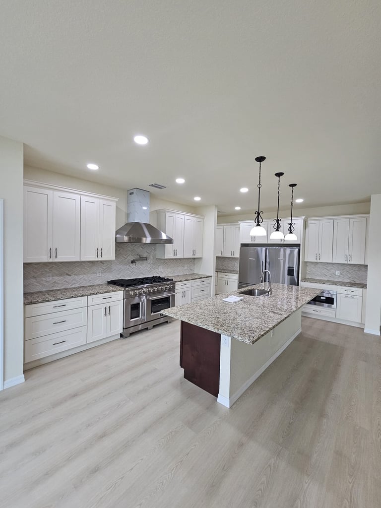 Kitchen renovation with white shaker cabinets, large center island, stainless steel appliances and light speckled countertops.