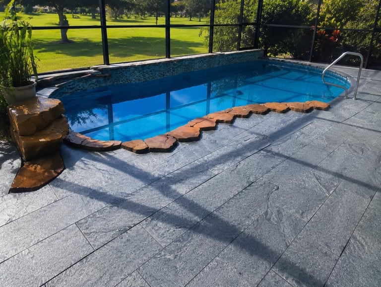 Sarasota pool deck update with textured gray decking and terracotta-colored edging inside a screened enclosure.