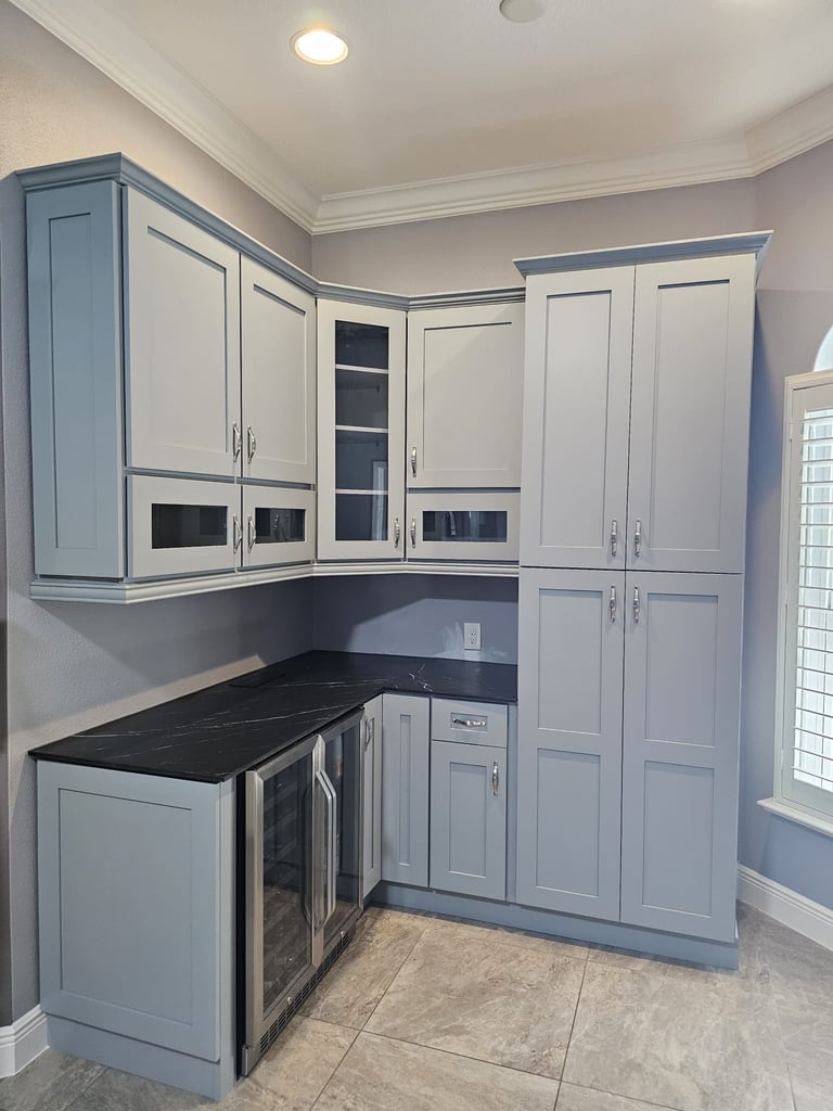 Kitchen remodel with white shaker cabinets, dark hardware, stainless steel appliances and gray backsplash.