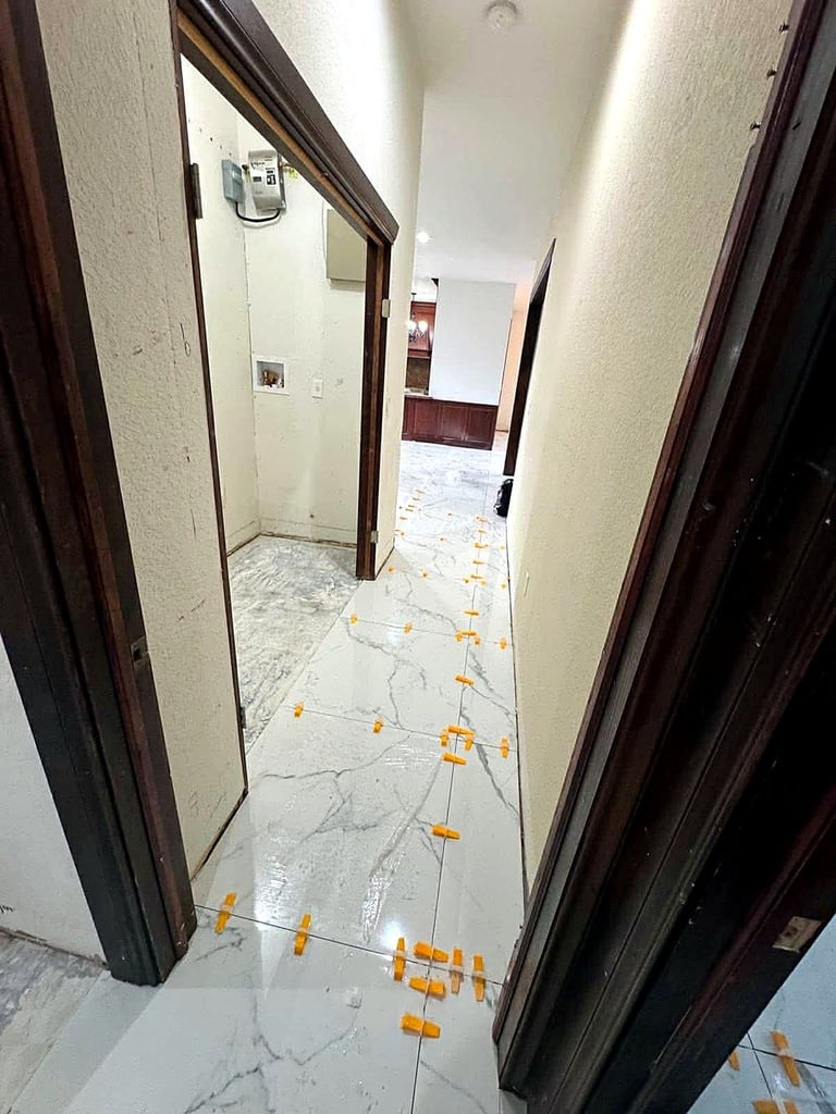 Marble-look porcelain hallway tile with leveling clips during installation in Siesta Key.