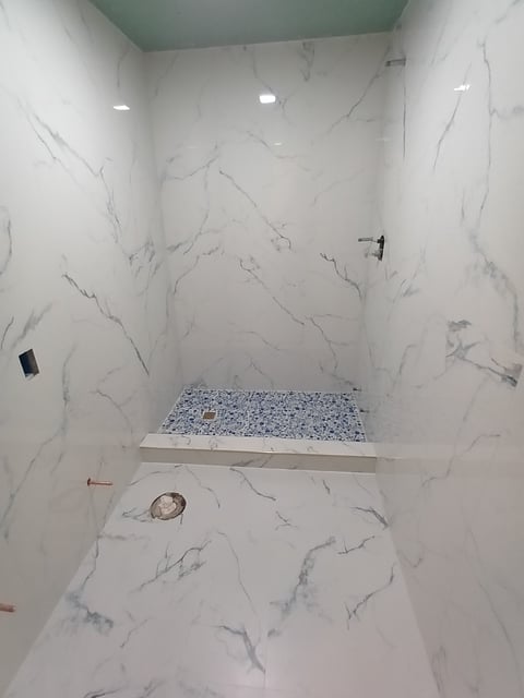Bathroom remodel in Venice showing marble-look wall and floor tile before final fixture installation.