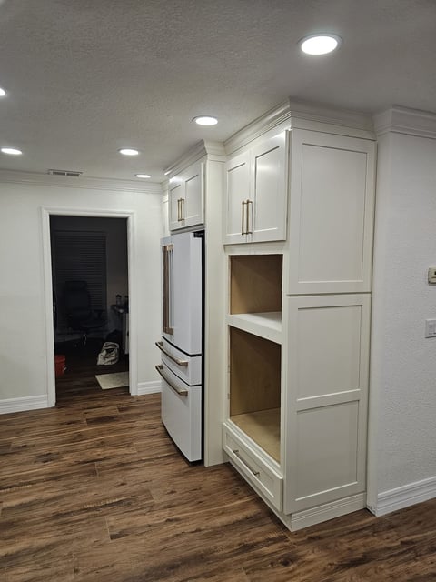 White full-height kitchen cabinetry with refrigerator surround and open appliance or storage niches.