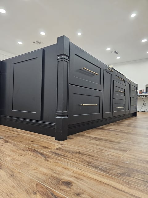 Close view of dark shaker kitchen island cabinetry with brass-toned drawer and cabinet pulls.